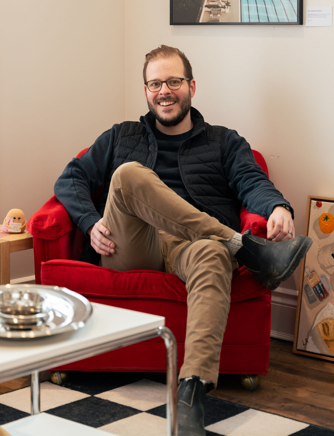 Dan, smiling, sitting sideways in a red armchair