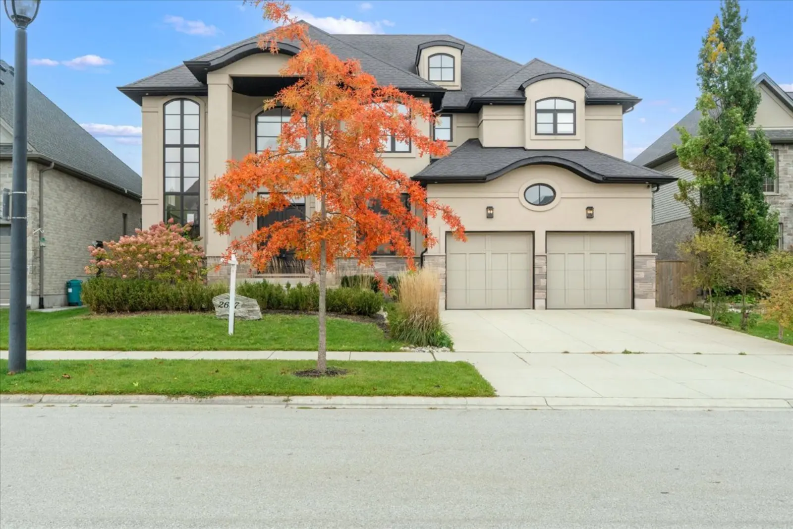 Front of the home: stone and stucco, two-car garage, a maple in fall colour