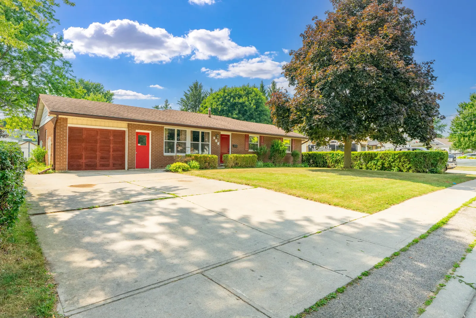 Brick bungalow with a double-wide concrete driveway and attached garage
