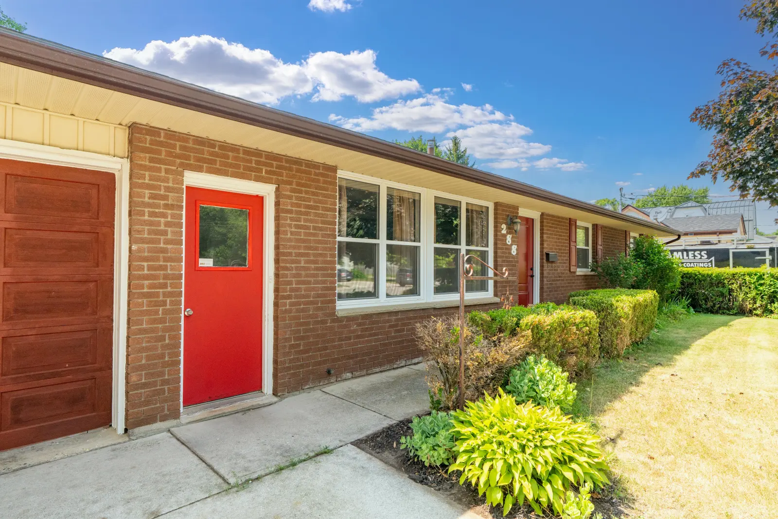 Red front door with brick and garden beds