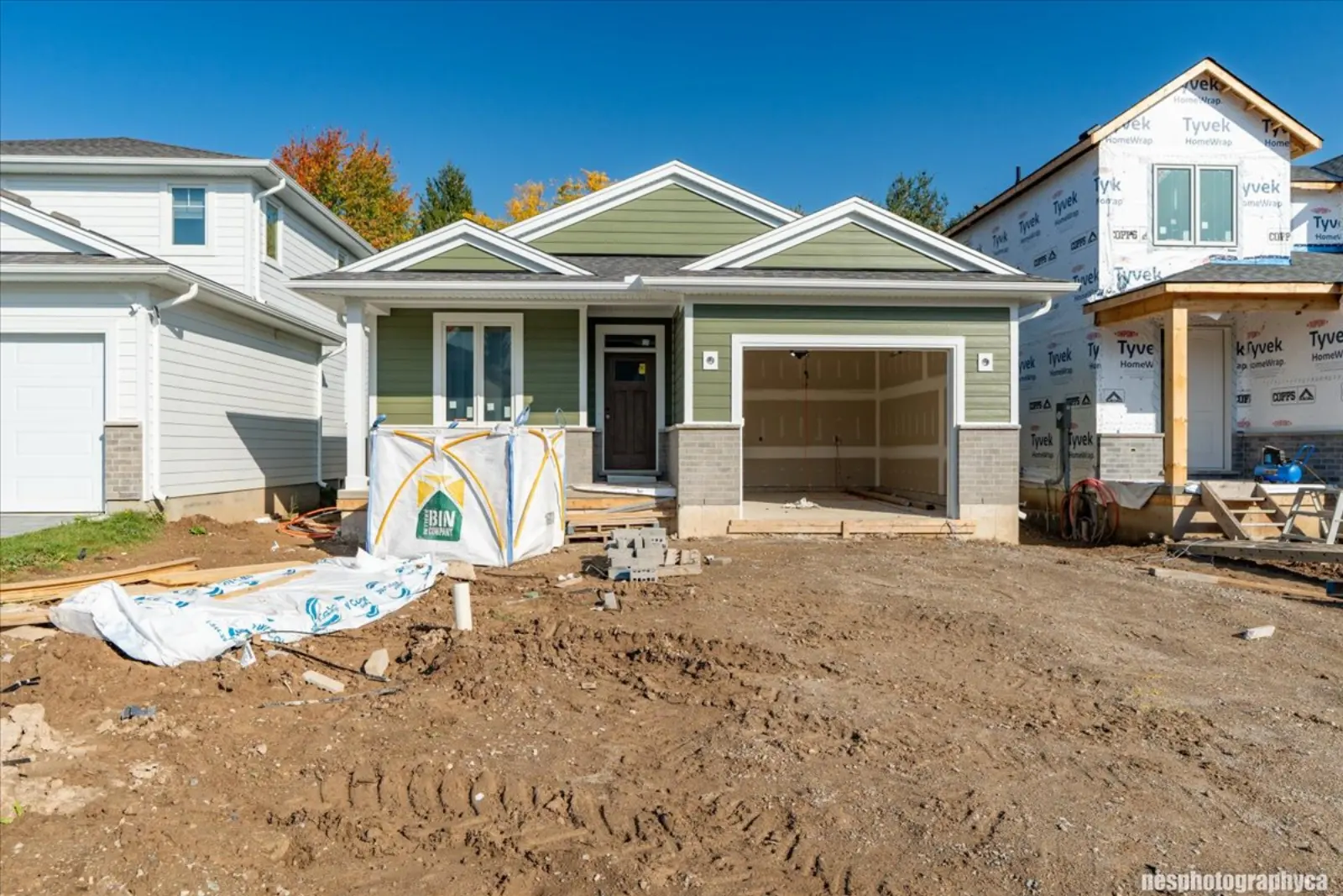 Front of the bungalow under construction: green siding, stone and a two-door garage