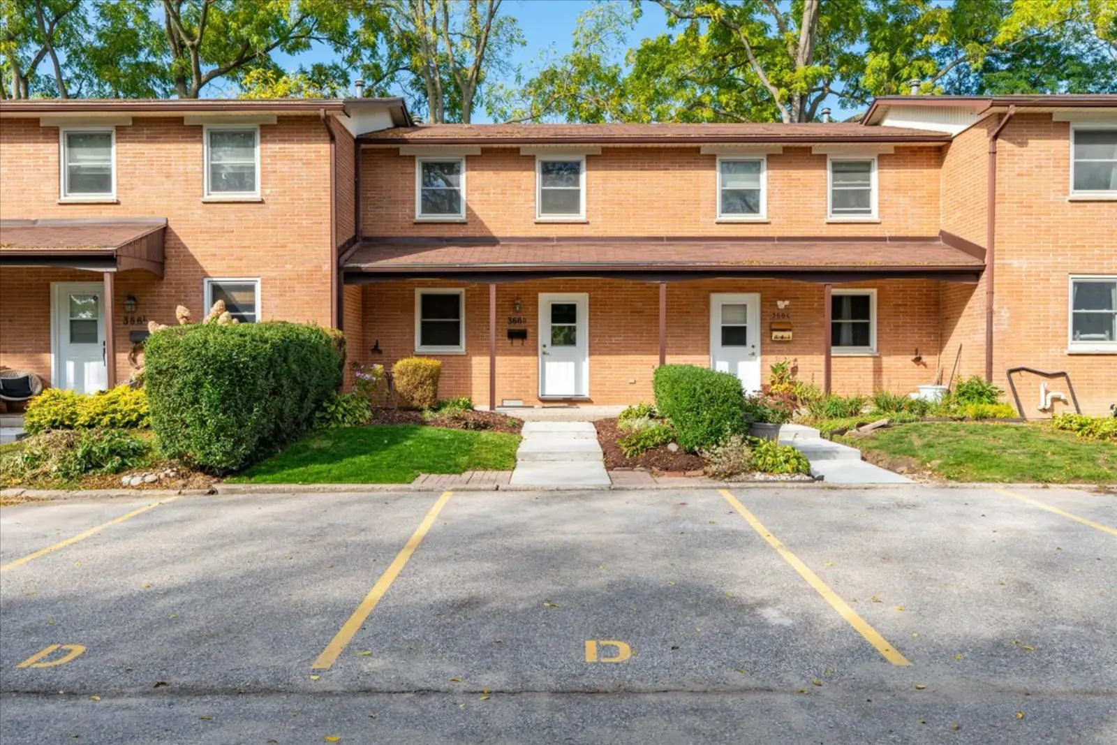 Front of the brick townhome row with parking out front