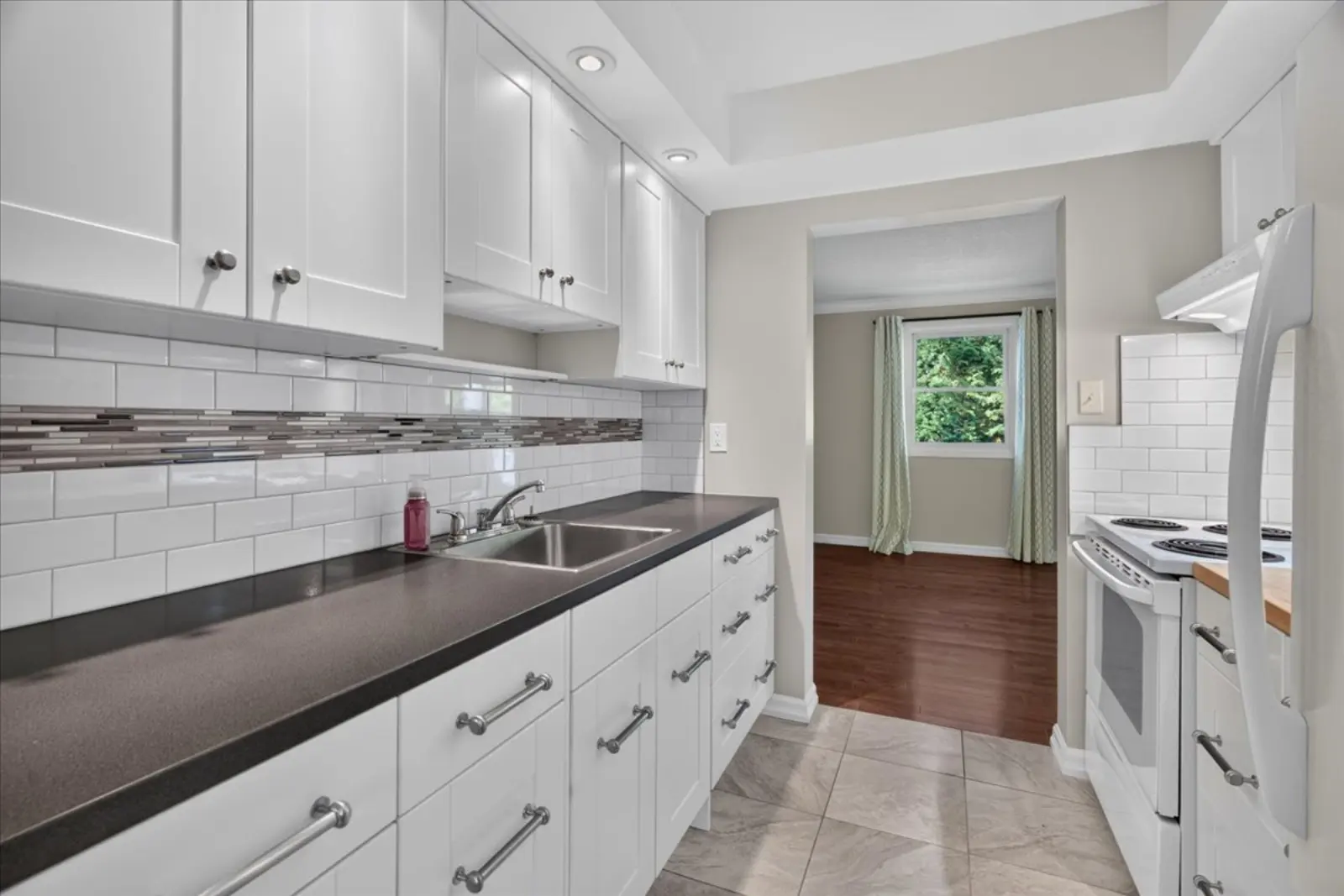 Galley kitchen with white cabinets and a subway tile backsplash