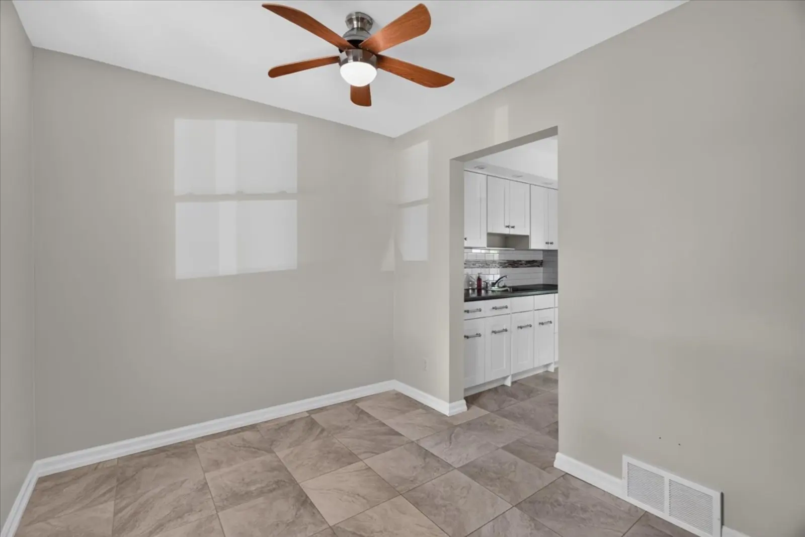 Room with a ceiling fan and a doorway to the kitchen