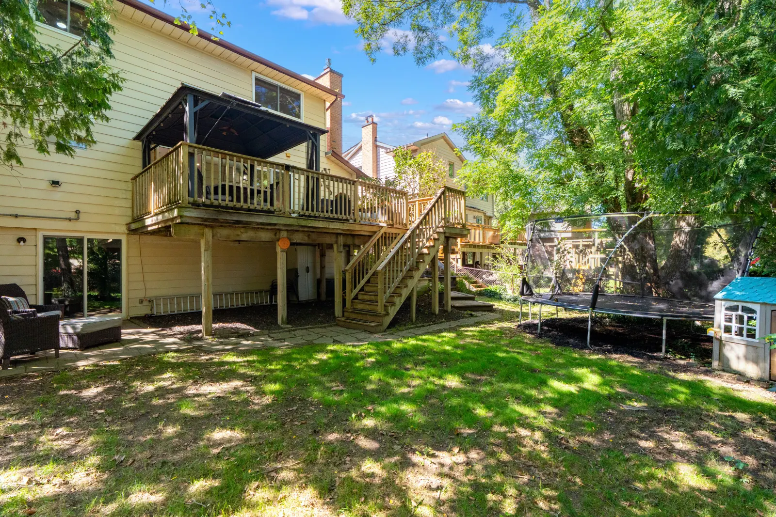 Back of the home with the deck and a green yard