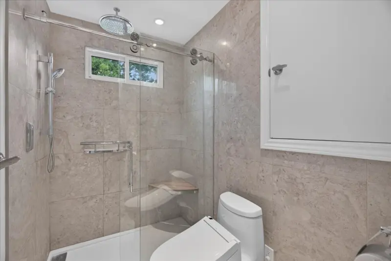 Tiled walk-in shower with a rain head and glass door