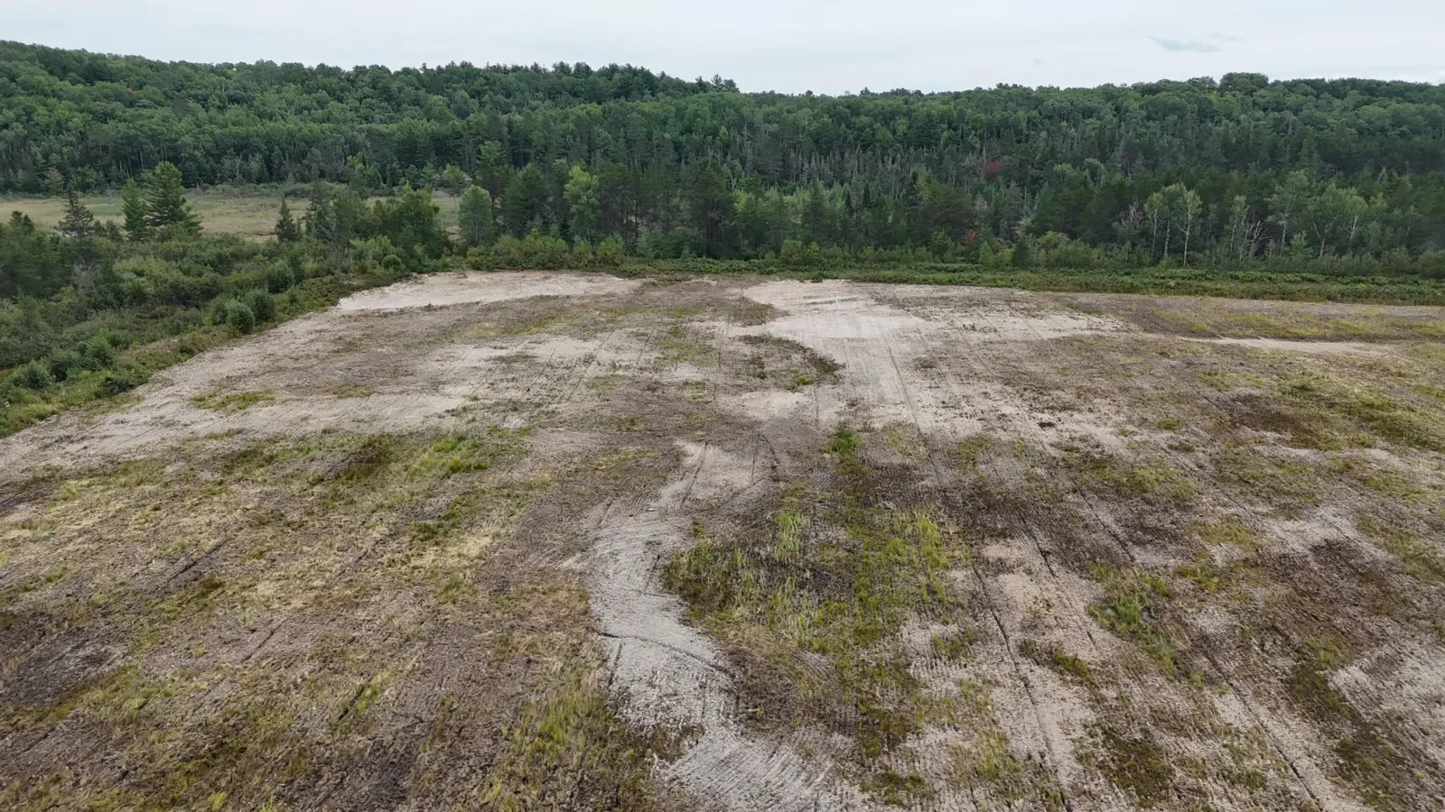 Open acreage from the air with trees on the far side