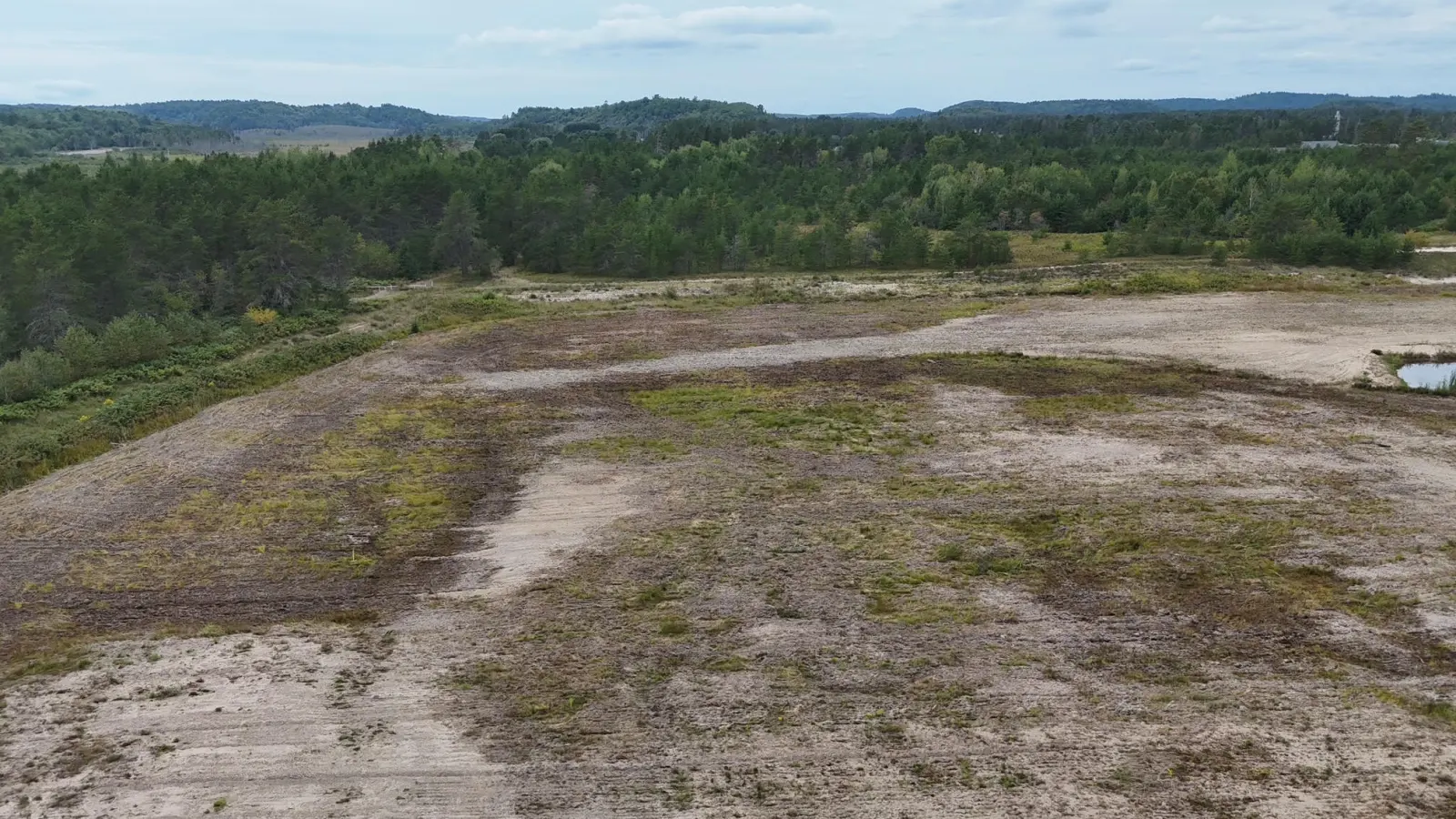 Open, level ground and wooded hills on the horizon